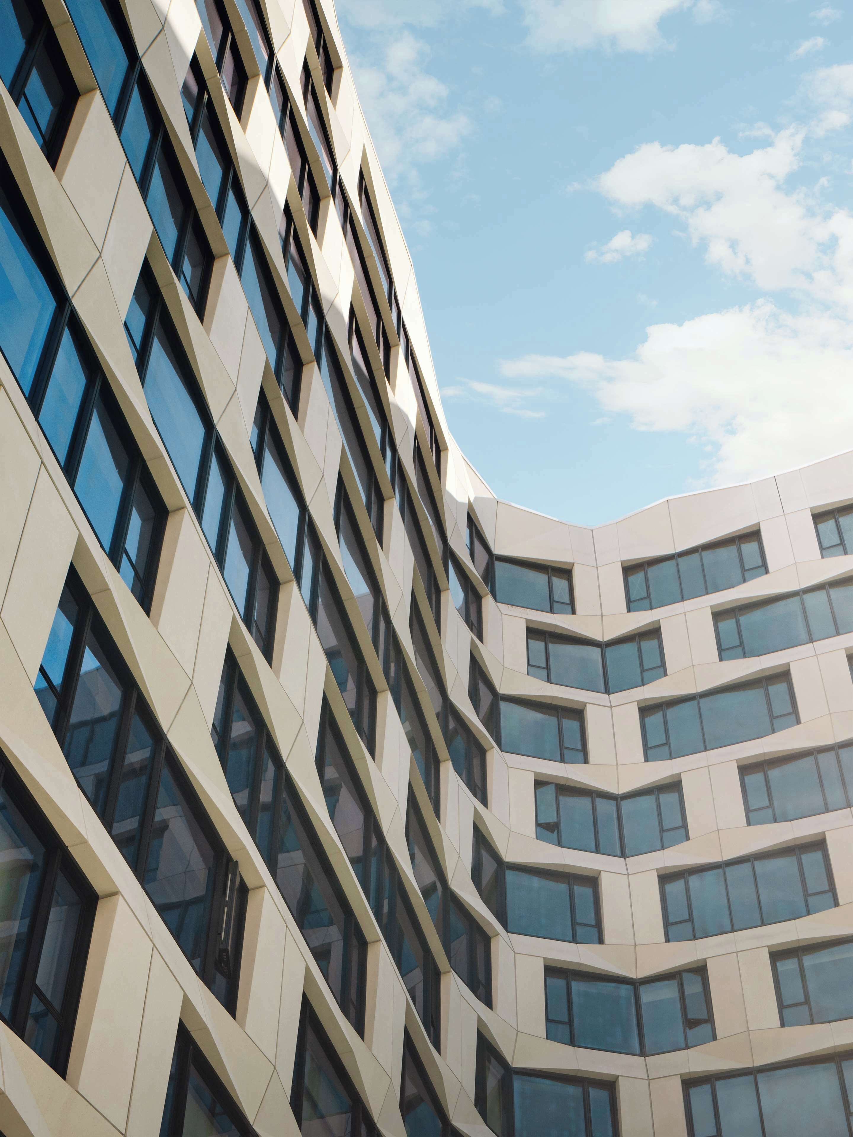 Ein modernes Gebäude mit einer gewölbten Fassade und zahlreichen Fenstern.