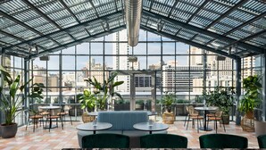 A modern indoor space with a glass ceiling, green seating, and potted plants.