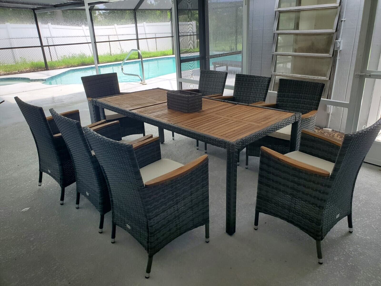 An outdoor patio with a pool, surrounded by wicker furniture and a glass door.