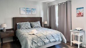 A bedroom with a bed, two bedside tables, a nightstand, a ceiling fan, and a window with curtains. - Free Heated Saltwater Pool, Kayaks, Bikes, Tennis Rackets and Fishing Poles! (North Port)