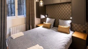 Ein Schlafzimmer mit einem großen Bett, einem Fenster mit Vorhängen, einem Deckenventilator und einer Wand mit Muster.