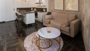 Eine moderne Küche mit Essbereich, ausgestattet mit einem runden Tisch mit goldener Basis, einer Couch und zwei Pendelleuchten.