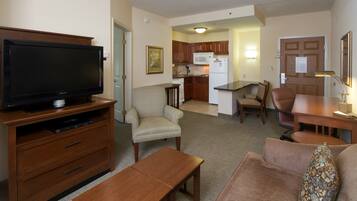 A living room with a flat-screen TV, wooden furniture, a sofa, and a dining area with chairs and a table.