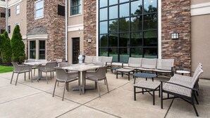 Une terrasse extérieure avec des meubles en osier et une grande baie vitrée.
