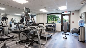Une salle de sport équipée de tapis de course, de vélos elliptiques, d’haltères et de ballons d’exercice.
