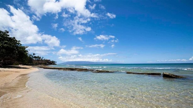 A beach with clear water, a sandy shore, and rocky outcrops. - Tropical Oasis By The Sea (Lahaina)