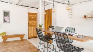 Una cocina moderna con encimera de madera, sillas de alambre negras e iluminación colgante.