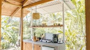 Cocina exterior equipada con estufa a gas, cafetera y diversos utensilios de cocina.