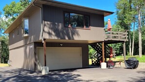 A two-story building with a garage, a covered outdoor seating area, and a covered patio. - 2 Bedroom Coach House, Green Lake, WI (Green Lake)