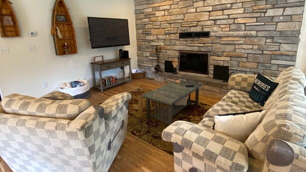A living room with a stone wall, a fireplace, and patterned furniture. - 2 Bedroom Coach House, Green Lake, WI (Green Lake)