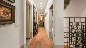 Un corridoio stretto con pavimento piastrellato, una porta a sinistra e un cancello decorativo in metallo a destra.