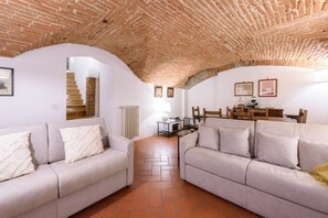 A living room with two sofas, a brick ceiling, white walls, and a staircase leading to an upper floor. - Santo Spirito Dream in Florence by Mmega (Firenze)