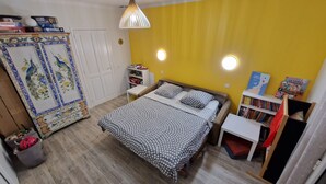Ein Schlafzimmer mit Bett, Kleiderschrank, Schreibtisch und Bücherregal.