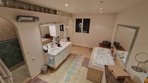 Ein Badezimmer mit zwei Waschbecken, einer Badewanne, einer Dusche und einem Spiegel.