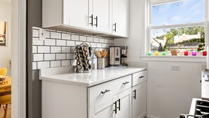 A kitchen with white cabinets, a tiled backsplash, and a window with a view of greenery outside. - Enjoy Chicago/suburbs 2BR townhouse fully equipped (Chicago)