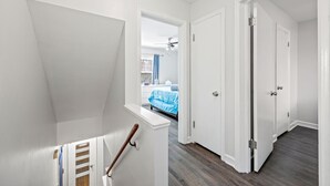 A hallway with white walls and a wooden floor, leading to a bedroom with a blue bedspread. - Enjoy Chicago/suburbs 2BR townhouse fully equipped (Chicago)