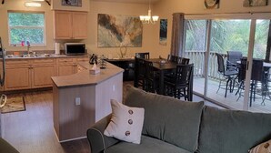 Une cuisine moderne avec des meubles en bois, un îlot central et un coin repas comprenant une table et des chaises.