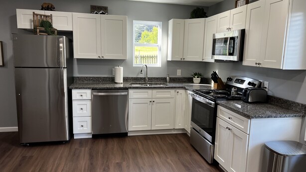 A modern kitchen with white cabinets, stainless steel appliances, and a granite countertop. - Conveniently Located Private Guesthouse in Wears Valley - No Cleaning Fees! (Sevierville)