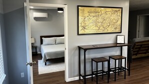 A bedroom with a bed, a desk with two stools, and a map on the wall. - Conveniently Located Private Guesthouse in Wears Valley - No Cleaning Fees! (Sevierville)
