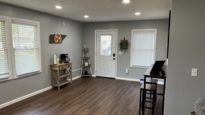 A spacious room with hardwood flooring, a desk, a chair, and a door with a window. - Conveniently Located Private Guesthouse in Wears Valley - No Cleaning Fees! (Sevierville)