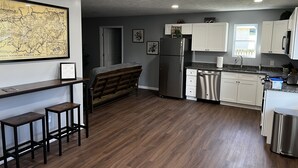 A modern kitchen with white cabinets, stainless steel appliances, and a wooden bench. - Conveniently Located Private Guesthouse in Wears Valley - No Cleaning Fees! (Sevierville)