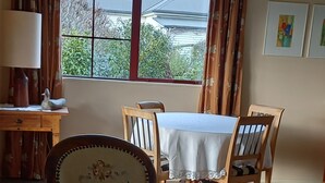 Un espace repas comprenant une table et des chaises, une lampe, et donnant sur l’extérieur.
