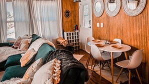 En hyggelig stue med en grøn sofa, hvide stole og et spisebord med tallerkener.