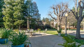 Eine Terrasse mit Gartenmöbeln, Blumentöpfen und Bäumen.