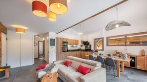 Een moderne woonkamer met een bank, eettafel en keuken op de achtergrond.