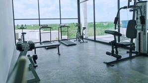 A gym with large windows, ceiling fan, and various exercise equipment. - MYA 1BR 001 (Tulum)