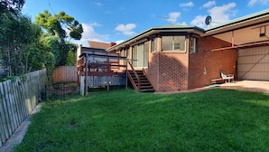 A residential backyard with a brick house, a wooden deck, and a garage. - City Edge Lower Plenty (Lower Plenty)