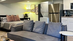 Un espace de vie compact comprenant un canapé, une petite table, un coin cuisine et un lit.