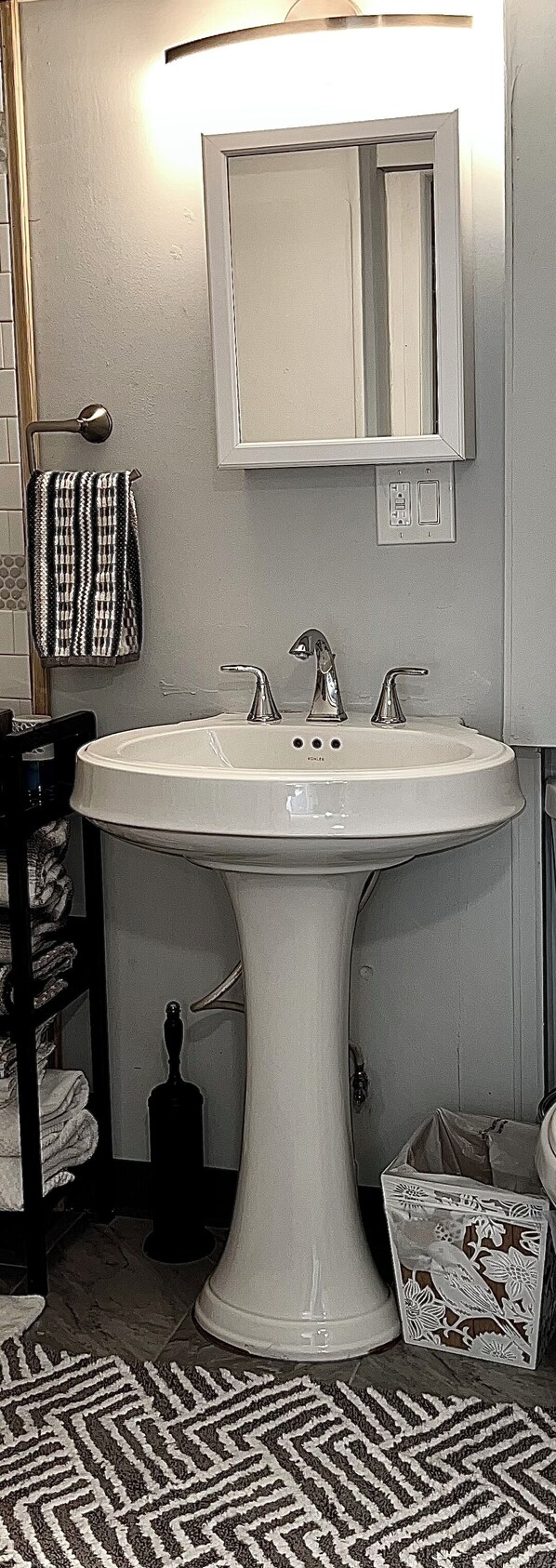 A bathroom with a pedestal sink, a mirror above it, and a towel rack with a patterned towel. - STUDIO apt.  nightly or monthly stays with washer, dryer, work space and WiFi (Philadelphia)