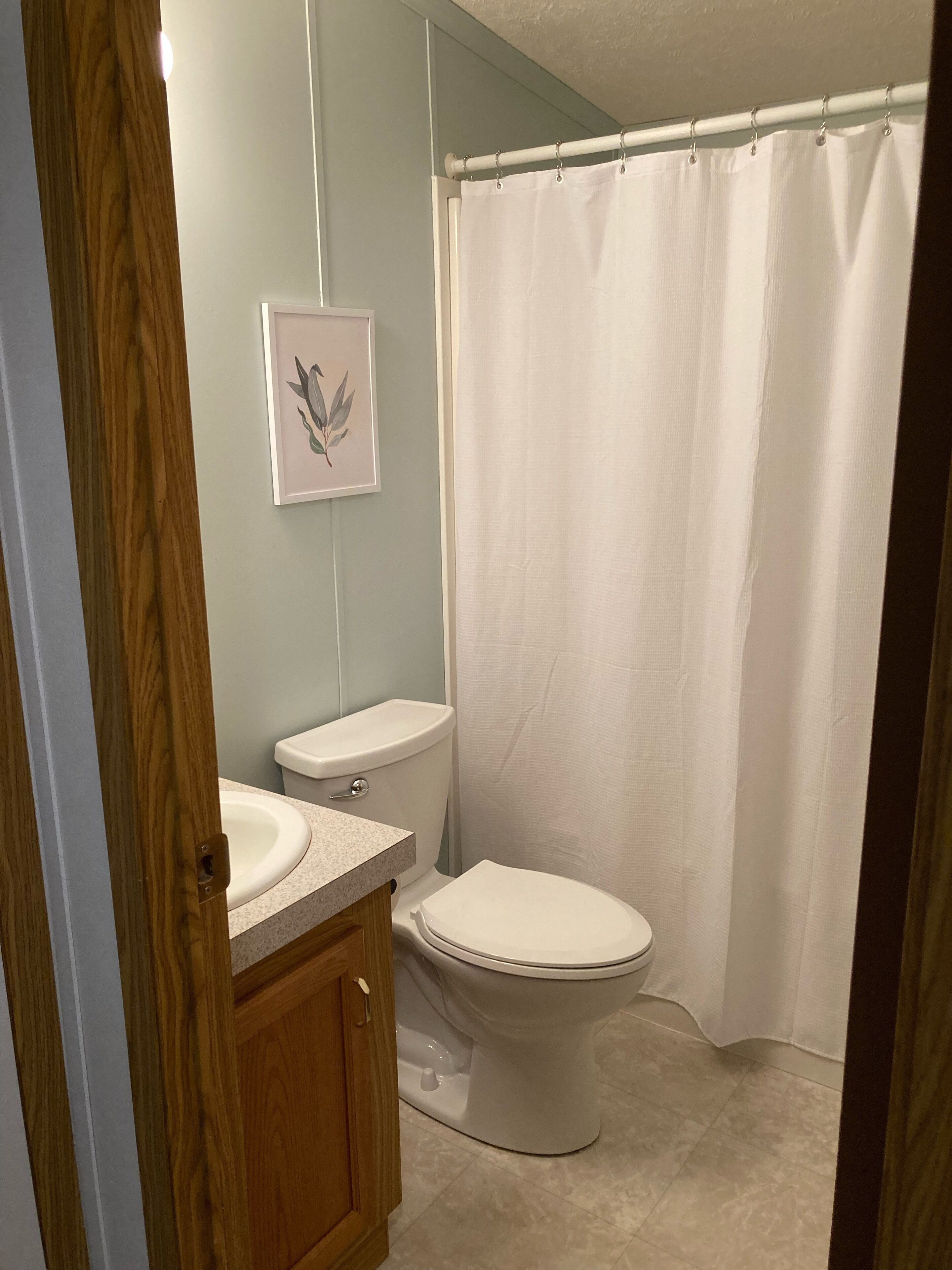 Un baño con inodoro, lavamanos y cortina de ducha.
