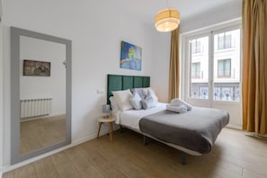 A hotel room with a bed, a nightstand, a lamp, a painting, a window with curtains, and a view of the outside. - 4br 2bth best location SOl, new (Madrid)