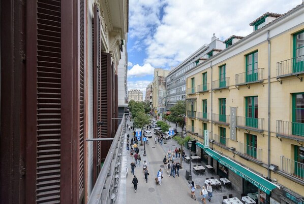 A bustling street scene with a restaurant named "CIDADE TUI" on the right, featuring outdoor seating and a clear view of the street.