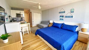 Une chambre compacte comprenant un lit, des tables de chevet, un bureau et un coin cuisine.
