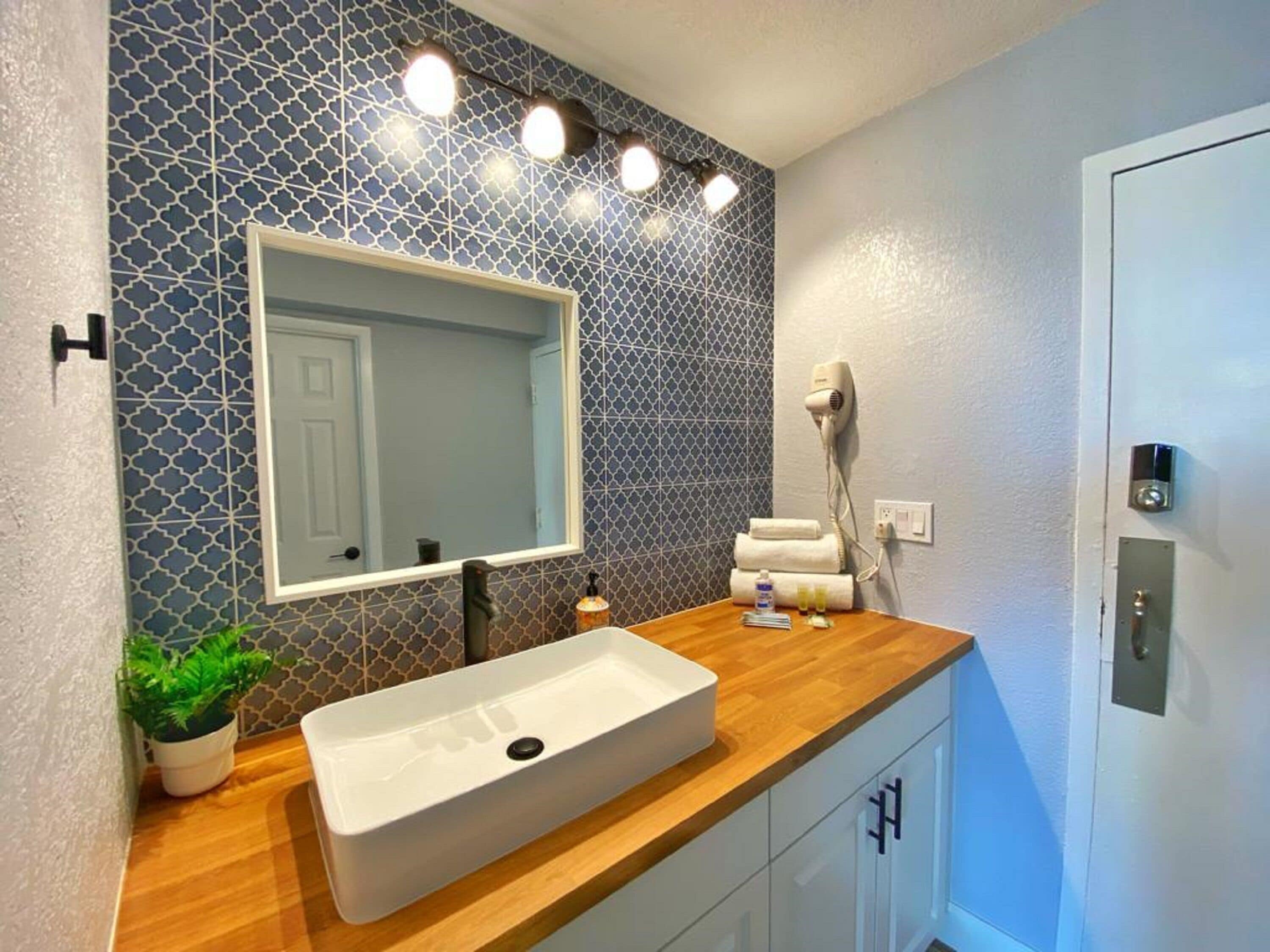 A bathroom with a white sink, a large mirror, a hairdryer, and a towel rack.