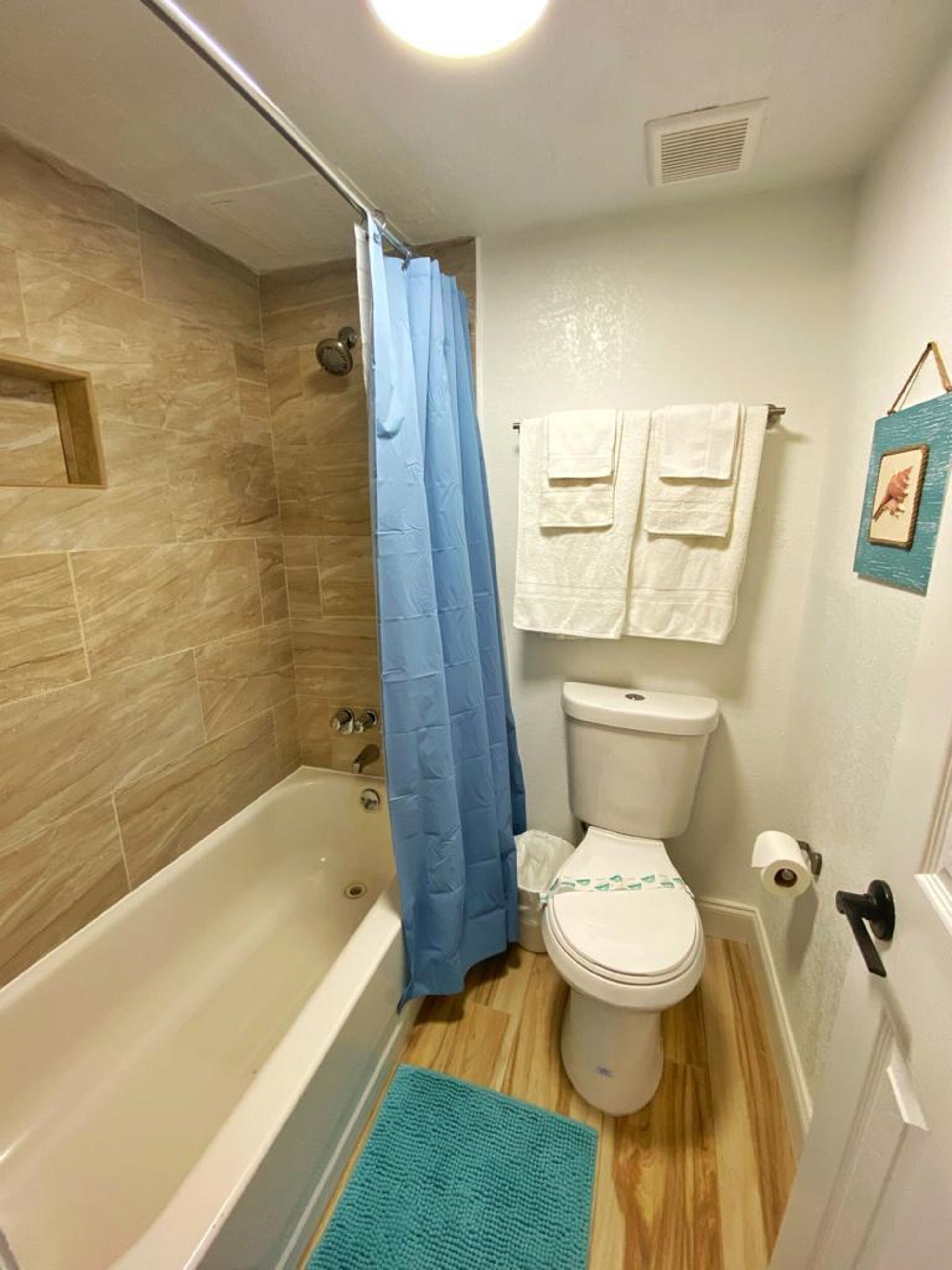 Une salle de bain avec une baignoire, des toilettes et un rideau de douche bleu.