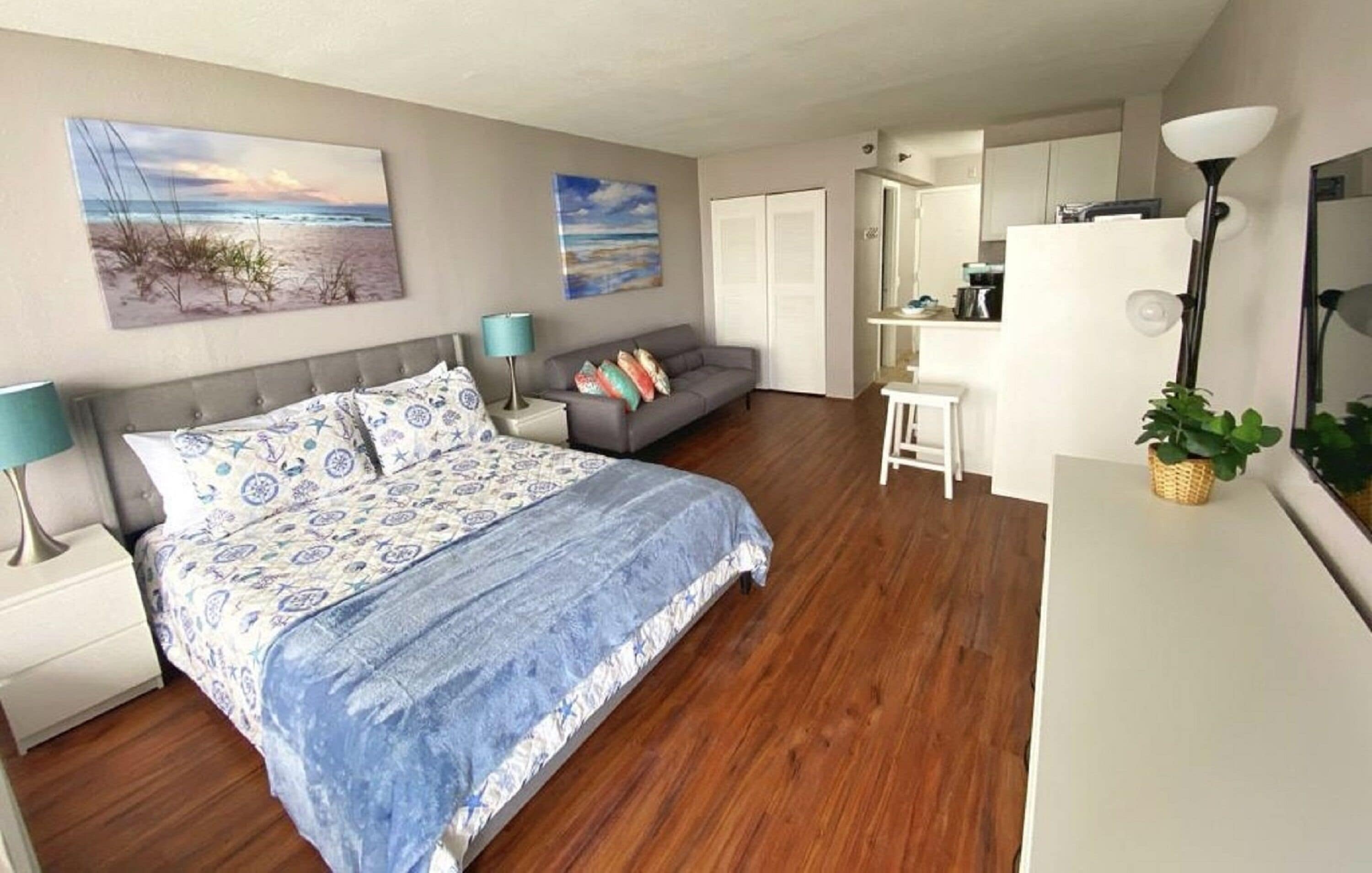 Ein modernes Schlafzimmer mit einem großen Bett, einem grauen Sofa und einer kleinen Schreibtischzeile.