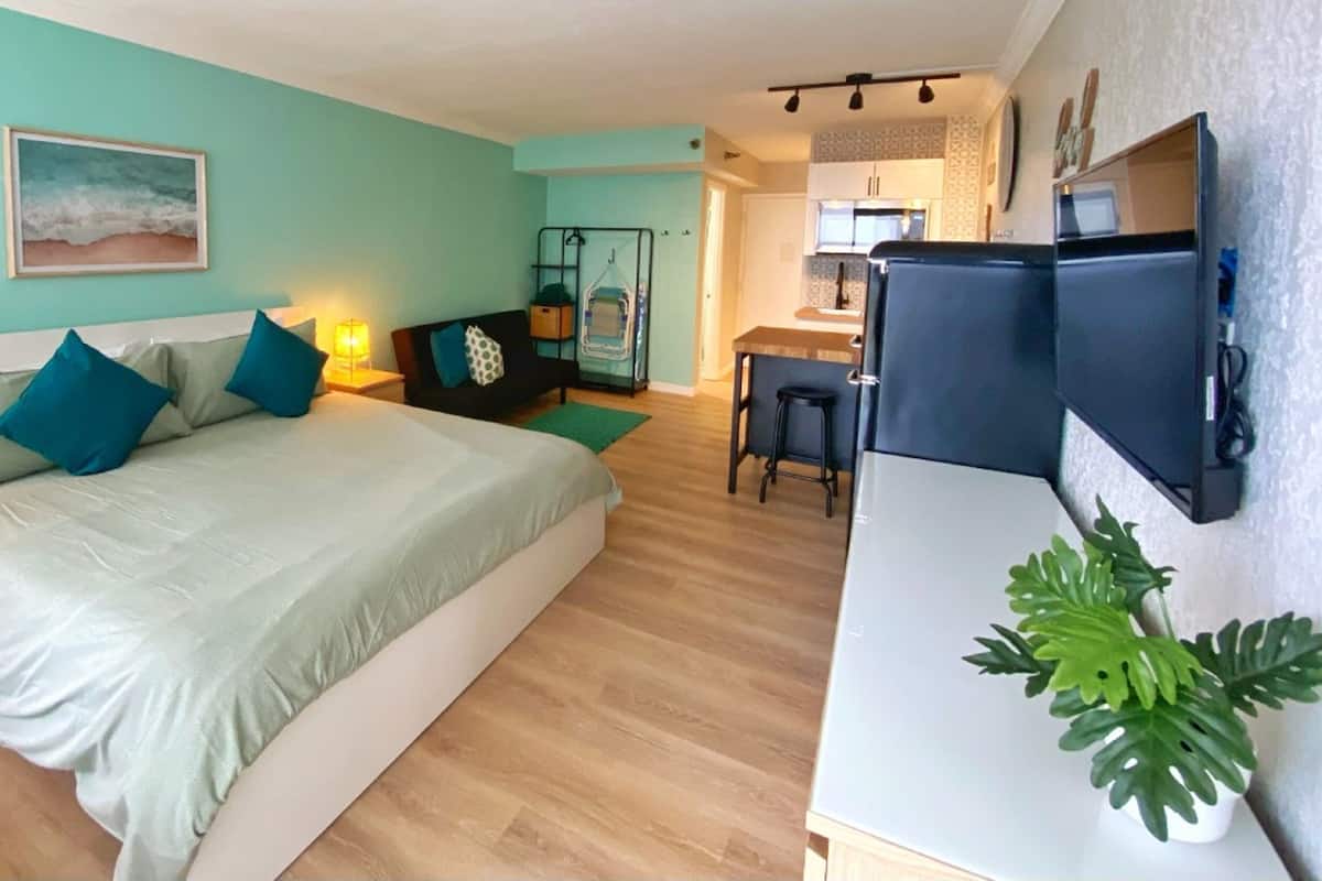 Een slaapkamer met een bed, nachtkastje en een bureau met stoel.