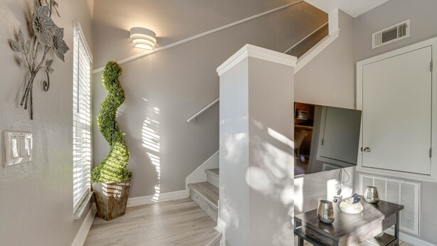 A staircase with a wooden finish, a wall-mounted light fixture, and a decorative plant.