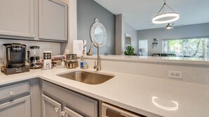 A modern kitchen with a large sink, stainless steel appliances, and a decorative mirror.