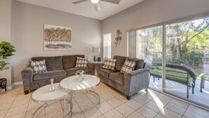 A living room with a sofa set, a glass coffee table, and a ceiling fan.