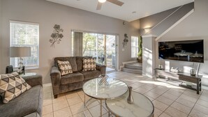 A living room with a sofa, coffee table, TV, and a ceiling fan.