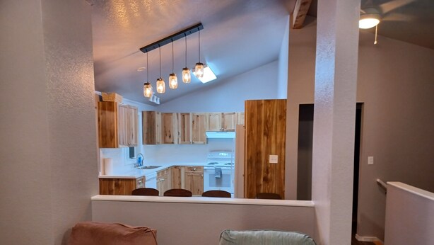 A compact living space with a kitchenette, a dining area with two chairs, and a small table. - Raven's Roost - Beaver Lake (Kodiak)