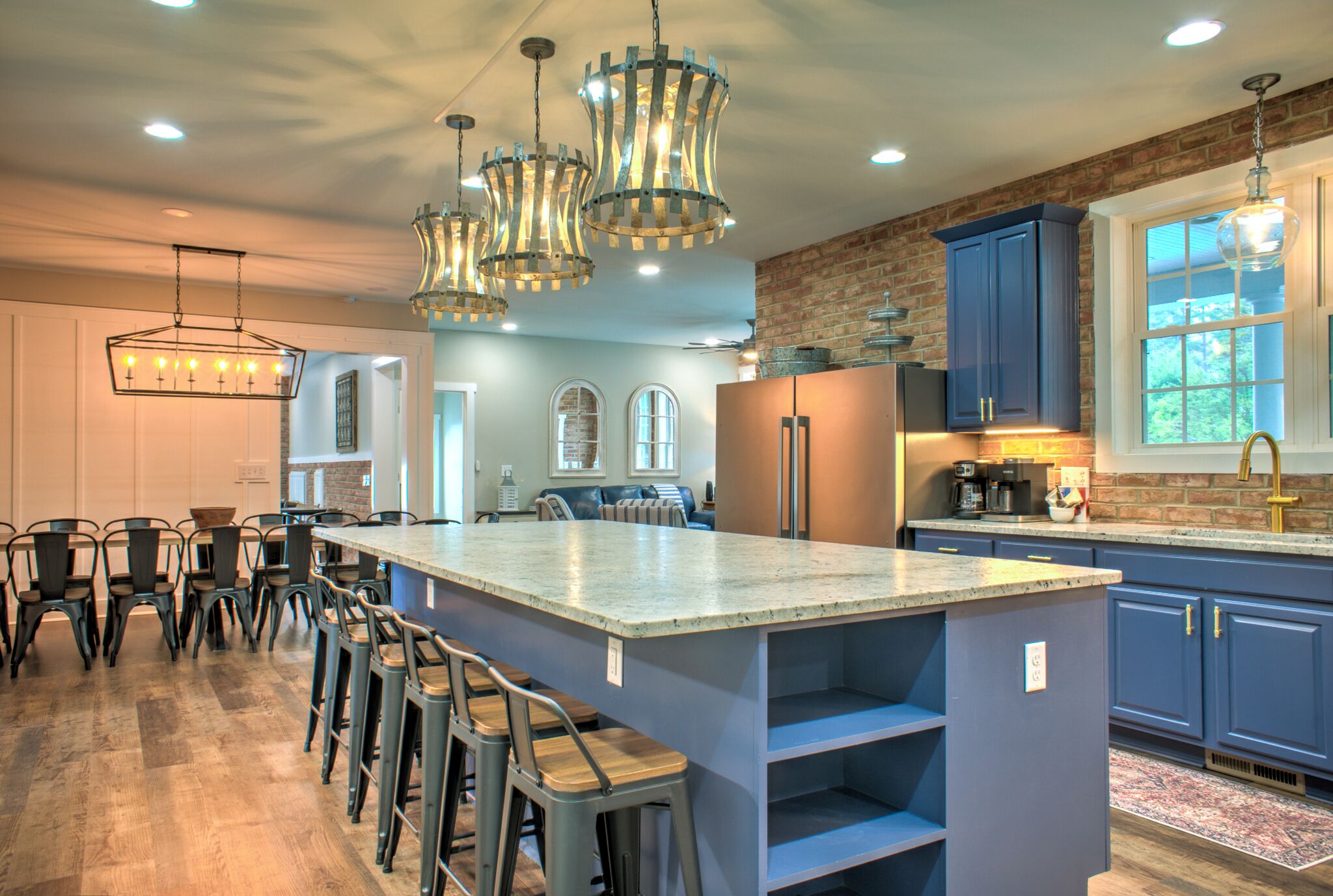 A spacious kitchen with a large island, bar stools, and modern lighting fixtures.