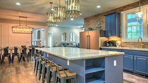 A spacious kitchen with a large island, bar stools, and modern lighting fixtures. - Brush Creek Pool House | Luxurious 10BR Home with Pool, Fire Pit, Game Room! (Fairview)