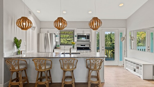 Une cuisine moderne dotée d’un îlot central, de tabourets de bar et de luminaires suspendus.