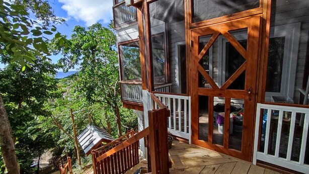 Une terrasse en bois avec un escalier menant à un espace abrité doté de grandes fenêtres.